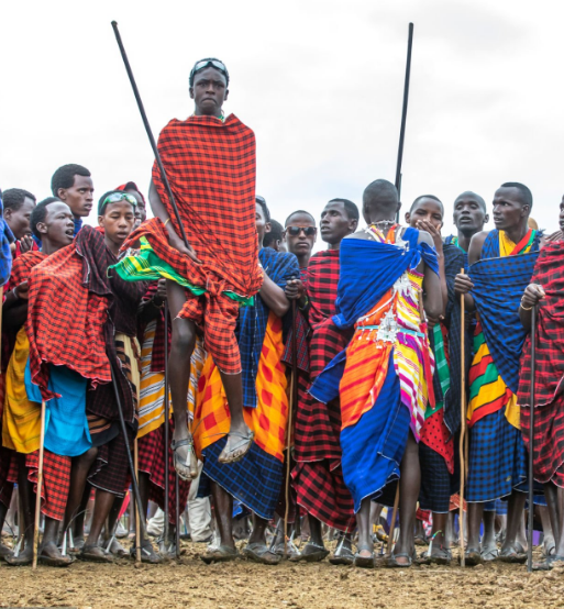 Maasai warrior in traditional attire performing a cultural dance in Tanzania's village.