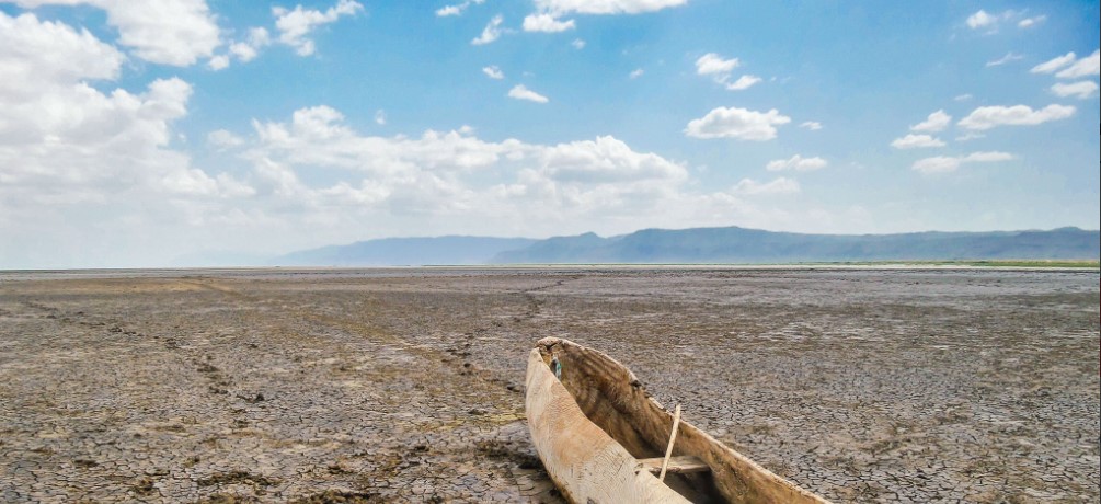 Tourists paddling a canoe on Lake Manyara with birds and wildlife visible along the shoreline.