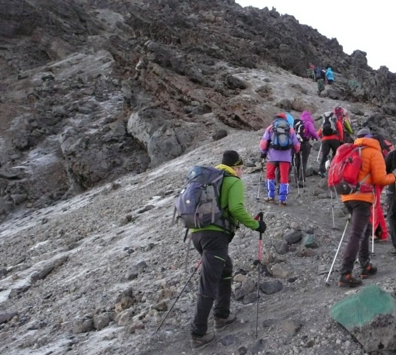 Trekking up Mount Kilimanjaro with scenic views of the landscape and hikers approaching the summit.