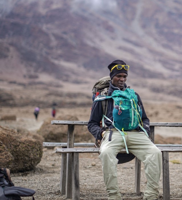 A Kilimanjaro guide leads trekkers across the Shira Plateau with snowcapped Uhuru Peak in the distance.
