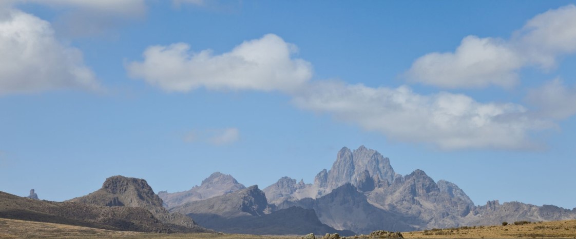 A determined climber standing triumphantly at Uhuru Peak on Mount Kilimanjaro, with snow-capped surroundings and a sunrise sky in the background.
