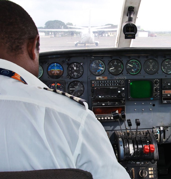 Passenger boarding a small domestic flight in Tanzania, with scenic landscapes in the background.