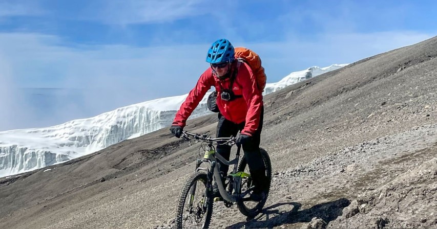 A determined hiker trains with a backpack on a mountain trail, preparing for Kilimanjaro’s summit