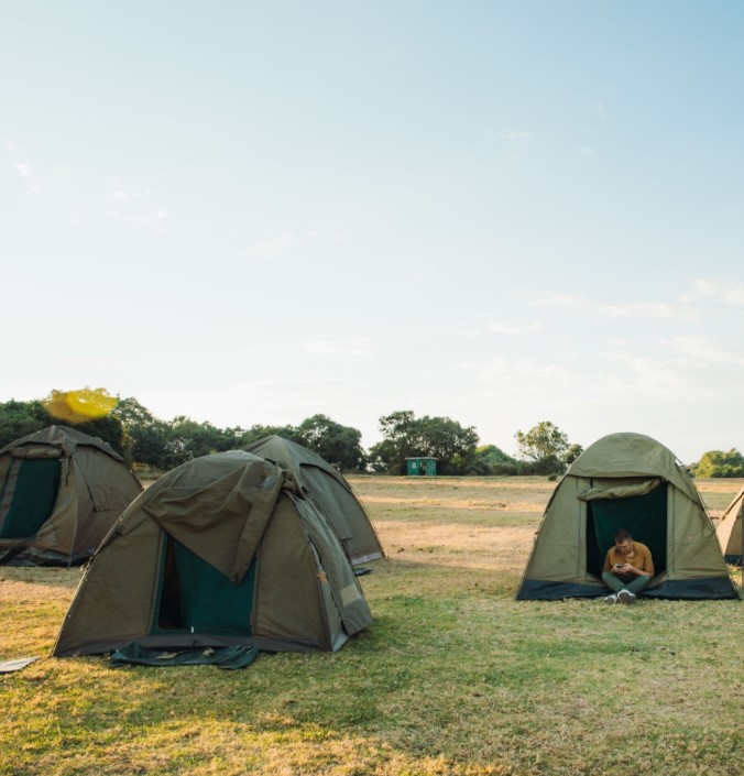 A budget safari camp tent set in the Tanzanian wilderness with scenic views of the savannah and distant wildlife.