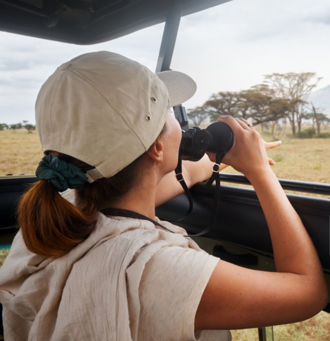 A DSLR camera with a zoom lens resting on a safari vehicle seat, ready to capture wildlife in Tanzania.