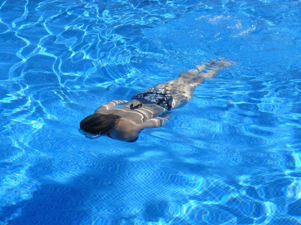 Snorkeler swimming beside a whale shark in clear waters off Mafia Island.